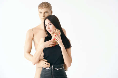 A young woman, dressed in a black leather skirt, and black boots on the tractor sole, the cheeks in the net. Posing with a disassembled male mannequin.の写真素材