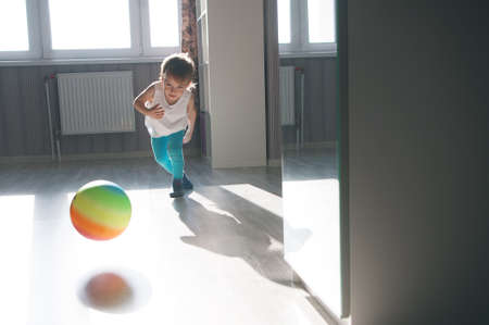 Child playing with a multicolored ball in the apartment.の写真素材