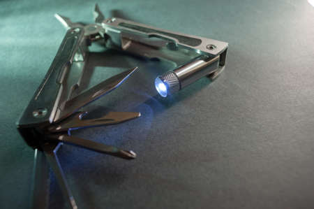 Combined pliers, multifunctional, with flashlight. Against the background of a gray texture.の写真素材
