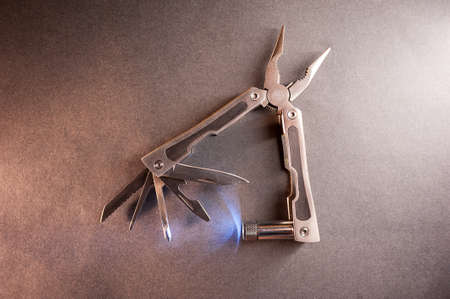 Combined pliers, multifunctional, with flashlight. Against the background of a gray texture.の写真素材