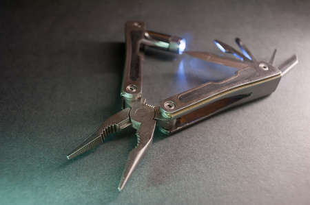 Combined pliers, multifunctional, with flashlight. Against the background of a gray texture.の写真素材