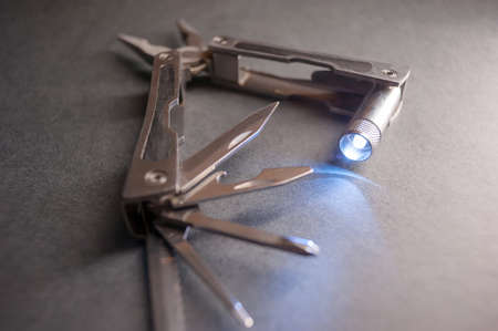 Combined pliers, multifunctional, with flashlight. Against the background of a gray texture.の写真素材