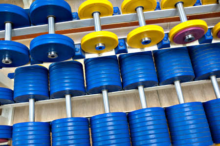 Dumbbells with yellow and red cargo disks in the gym lie in a row.の写真素材