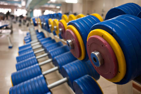 Dumbbells with yellow and red cargo disks in the gym lie in a row.の写真素材