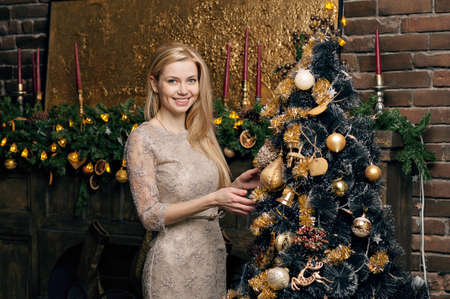 Young woman in a cozy interior of Christmas. The girl near a Christmas tree among many gifts.の写真素材