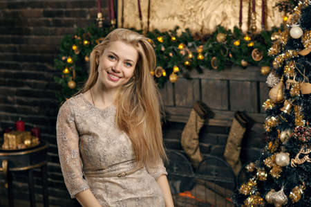 Young woman in a cozy interior of Christmas. The girl near a Christmas tree among many gifts.の写真素材