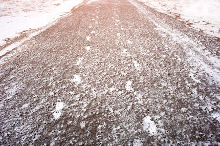 Snow traces of two people on an asphalt path in the city. Abstract silhouette of a persons tracks on a road in winterの写真素材
