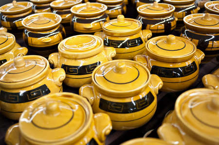 Ceramic mugs and bowls of yellow-brown color in the store on the counter stand in a pile. Sale, trade.の写真素材