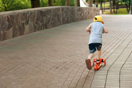 boy 5 years old, with a scooter on the road in the park. family holidayの写真素材