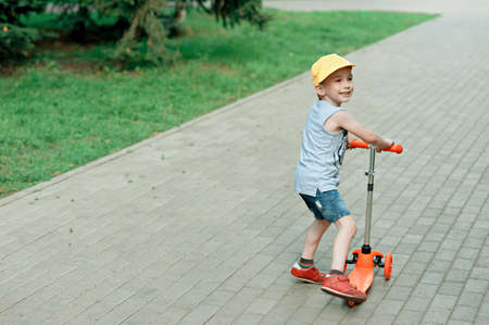 boy 5 years old, with a scooter on the road in the park. family holidayの写真素材