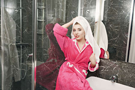 A beautiful young girl in a pink dressing gown and a white towel on her head, after a shower. Wellness and Spa concept.の写真素材