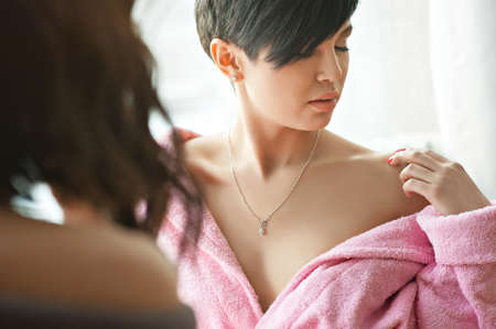 Two happy sexy young women, friends, in dressing gowns, sit at the window, on the floor, face to face. Unconventional coupleの写真素材