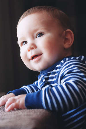 Portrait of an adorable young boy, with a smile on his face, against a dark background.の写真素材