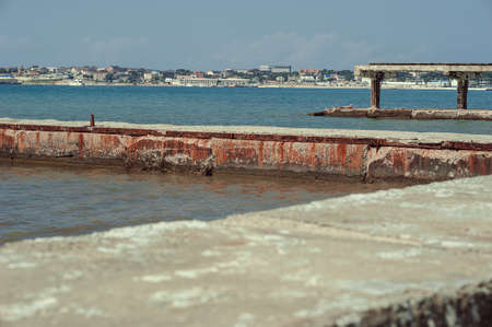 Rusty old iron mooring bollards, mounted on a concrete pier in the backgroundの写真素材