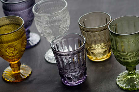 a set of transparent, crystal glasses of different colors, on a dark wood table.の写真素材