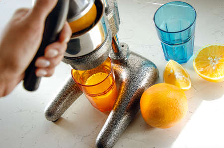 Close up of young woman hands doing fresh lemonade, squeezing juice from citrus fruit, juicer.の写真素材
