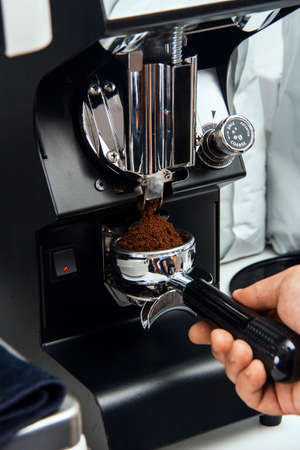 freshly ground coffee beans in a portafilter by the coffee grinderの写真素材
