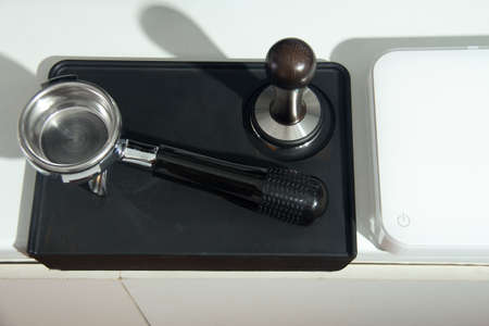 Man is using a tamper to press freshly ground morning coffee into a coffee tabletの写真素材