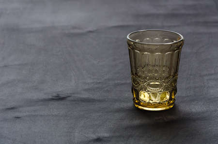 transparent, crystal glass of golden color, on a dark wooden tableの写真素材