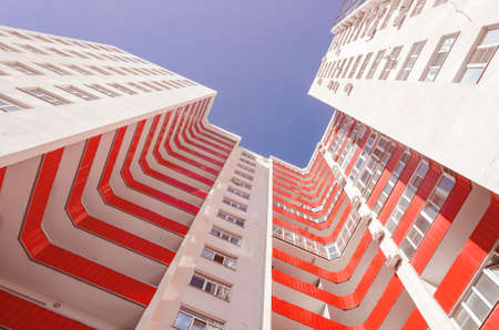 View of a residential building from the bottom up. White house with red balconies in a warm sunny dayの写真素材