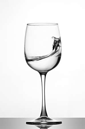 A splash of crystal clear water in a glass for wine. Water splashes. Drinking water. Alcoholの写真素材