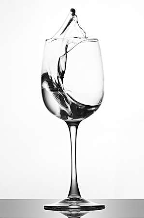 A splash of crystal clear water in a glass for wine. Water splashes. Drinking water. Alcoholの写真素材