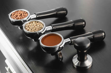 four holders with green, roasted, ground, and hot coffee and tamper, equipment for making freshly brewed coffeeの写真素材