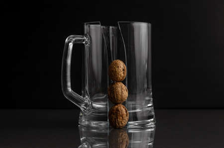 cracked beer mug with three walnuts on a dark backgroundの写真素材