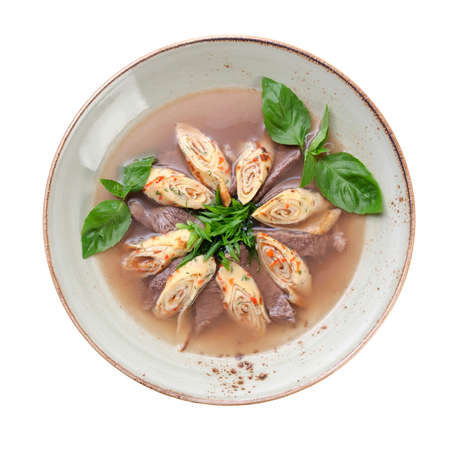 soup with slices of beef, and pancakes rolled into a roll, decorated with greens. isolated on white backgroundの写真素材