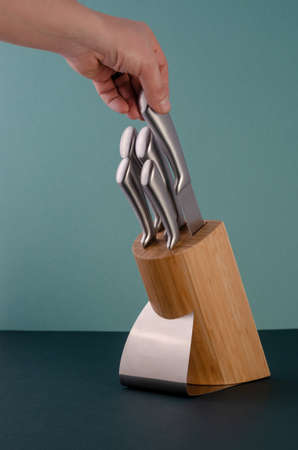 Woman Hands Pulling Out Stainless Steel Chefs Knives From A Bamboo Standの写真素材