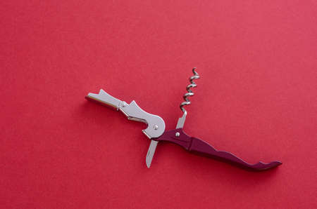 Opened sommeliers knife with corkscrew and bottle opener, waiters knife professional, on red backgroundの写真素材