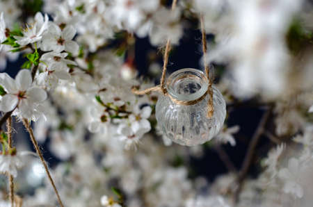 Original wedding flower decorations in the form of mini-vases and bouquets of flowers, hanging on a flowering branchの写真素材