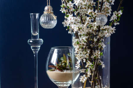 Original wedding flower decorations in the form of mini-vases and bouquets of flowers, hanging on a flowering branchの写真素材