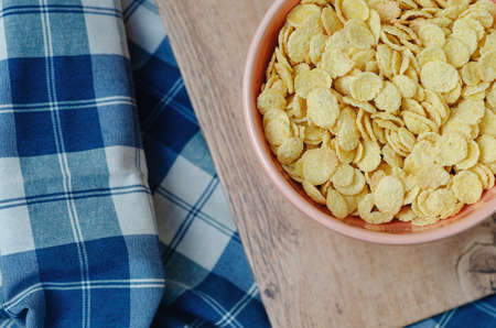 Cornflakes in a pink bowl, on a wooden table. copy spaceの写真素材