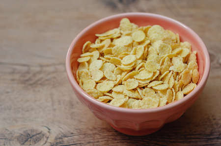 Cornflakes in a pink bowl, on a wooden table. copy spaceの写真素材