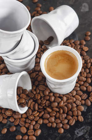 Ceramic cups look like crumpled paper espresso coffee cups and sprinkled roasted coffee beansの写真素材
