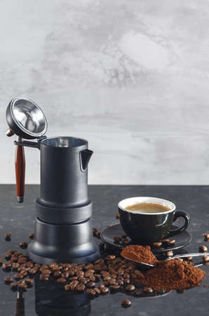 Coffee maker Type geyser and black colored coffee cup, with coffee beans and freshly ground coffee in a spoonの写真素材