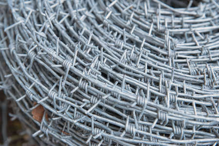 Close up on a pile roll of shiny new barbed wire for fence fencing. Security protection law enforcement. Prison jail criminal offense locked upの写真素材