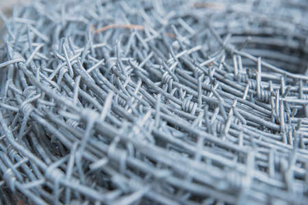 Close up on a pile roll of shiny new barbed wire for fence fencing. Security protection law enforcement. Prison jail criminal offense locked upの写真素材