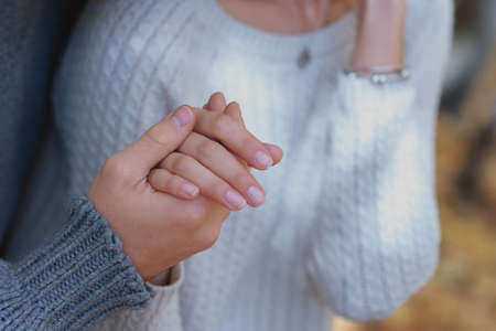 A man in love holds the palm of his woman, dressed in knitted sweaters. close-up. shallow depth of field. copy space.の写真素材