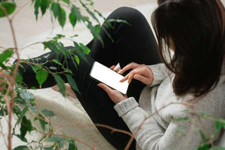 A woman at home, with a phone in her hands. Copyspace.の写真素材