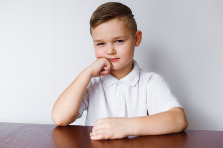 The little boy looks with suspicion and distrust. The schoolboy looks suspiciously. Portrait on a...