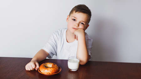 The young boy was tired of waiting. Morning, healthy breakfast, homemade milk and a delicious bagel. The boy is tired.の写真素材