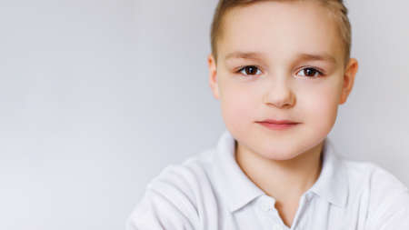 Portrait of a young boy of caucasian against a white wall.