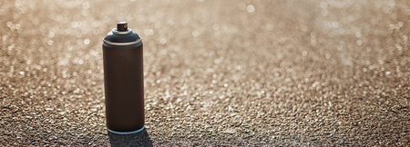 Spray can for painting stands on the asphalt. The sun is shining.