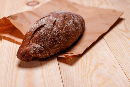 Homemade bread on a paper bag. The baked product on the wooden table.の写真素材