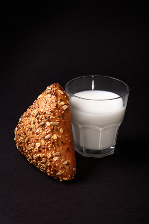 Fresh seed bun and tasty glass of milk isolated on black background.の写真素材