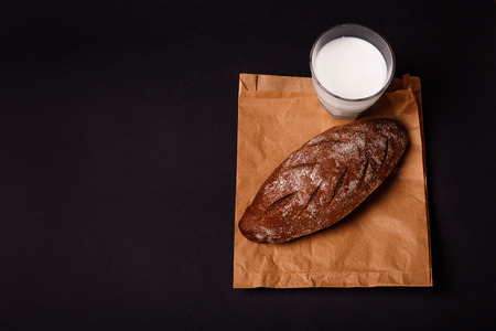 Tasty wheat bread with milk on dark background. Copy space