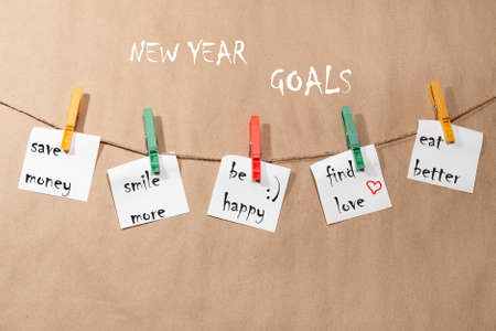 New Year's goals. Stickers hanging on a rope attached with red and green clothespins, on a paper...