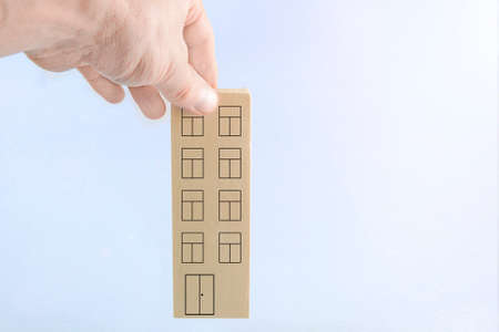 on a light blue background, the hand puts a multi-storey building.